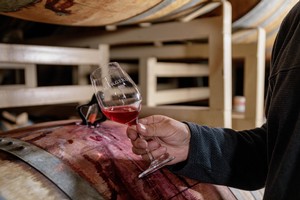 Doug Margerum holding a glass of wine next to a wine barrel at the Margerum Wine Company location in Buellton California
