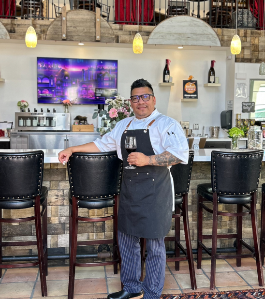 David Jimenez standing in front of the wine bard holding a glass of wine
